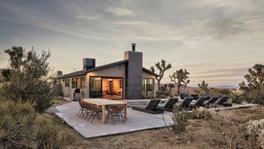 Une maison moderne dotée d’un patio, d’une piscine et de mobilier d’extérieur.