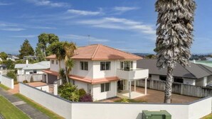 A modern two-story house with a red-tiled roof, a balcony, and a well-maintained lawn. - Spacious 3 brm home for families to enjoy in Tauranga ga (Tauranga)