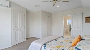 A bedroom with a bed, white walls, and a ceiling fan. - Spacious 3 brm home for families to enjoy in Tauranga ga (Tauranga)