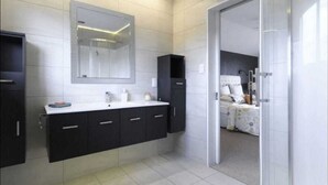 A modern bathroom with a large mirror, dark cabinets, and a white countertop. - Spacious 3 brm home for families to enjoy in Tauranga ga (Tauranga)