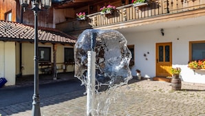Une cour avec un élément décoratif aquatique, un lampadaire et un bâtiment doté de balcons et de jardinières.