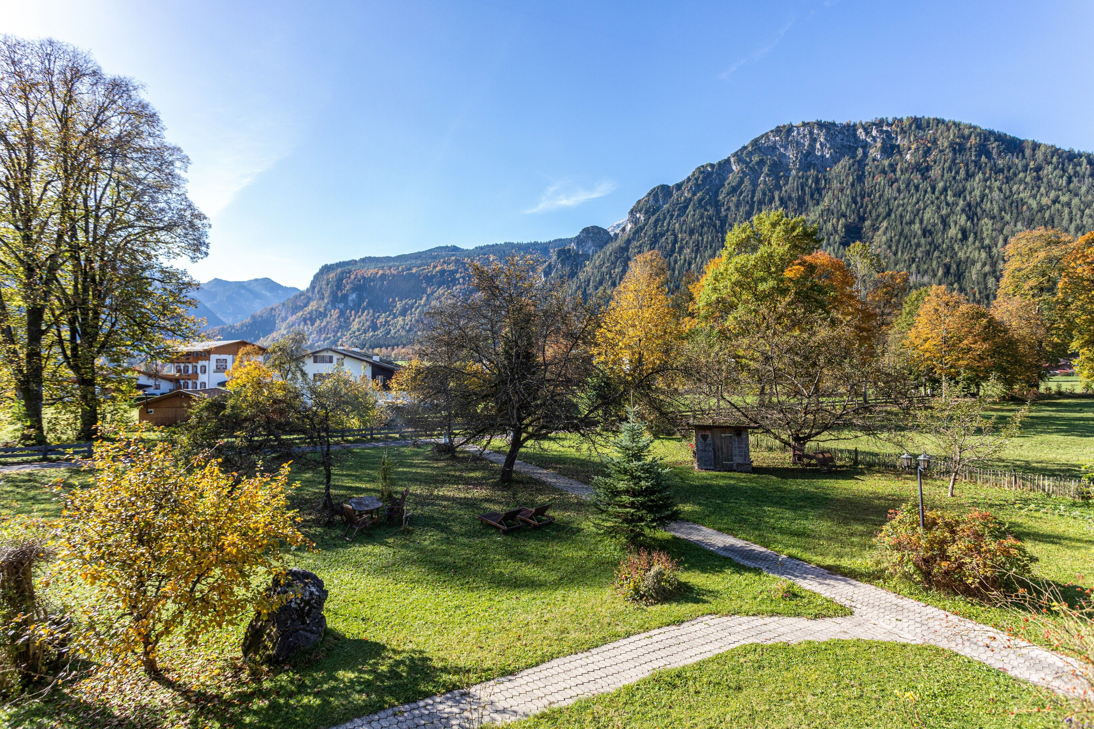 A rural landscape with a paved path, a small building, and a mountain in the background.