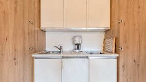 Cozinha compacta com armários de madeira, cafeteira e lava-louças.