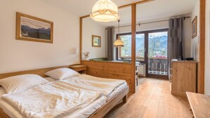 Quarto com cama de madeira, mesa de cabeceira, guarda-roupa de madeira e janela com vista para montanhas.