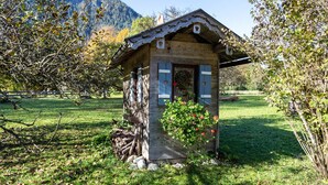 Een houten chalet met een schuin dak, een klein terras en een bloembak.