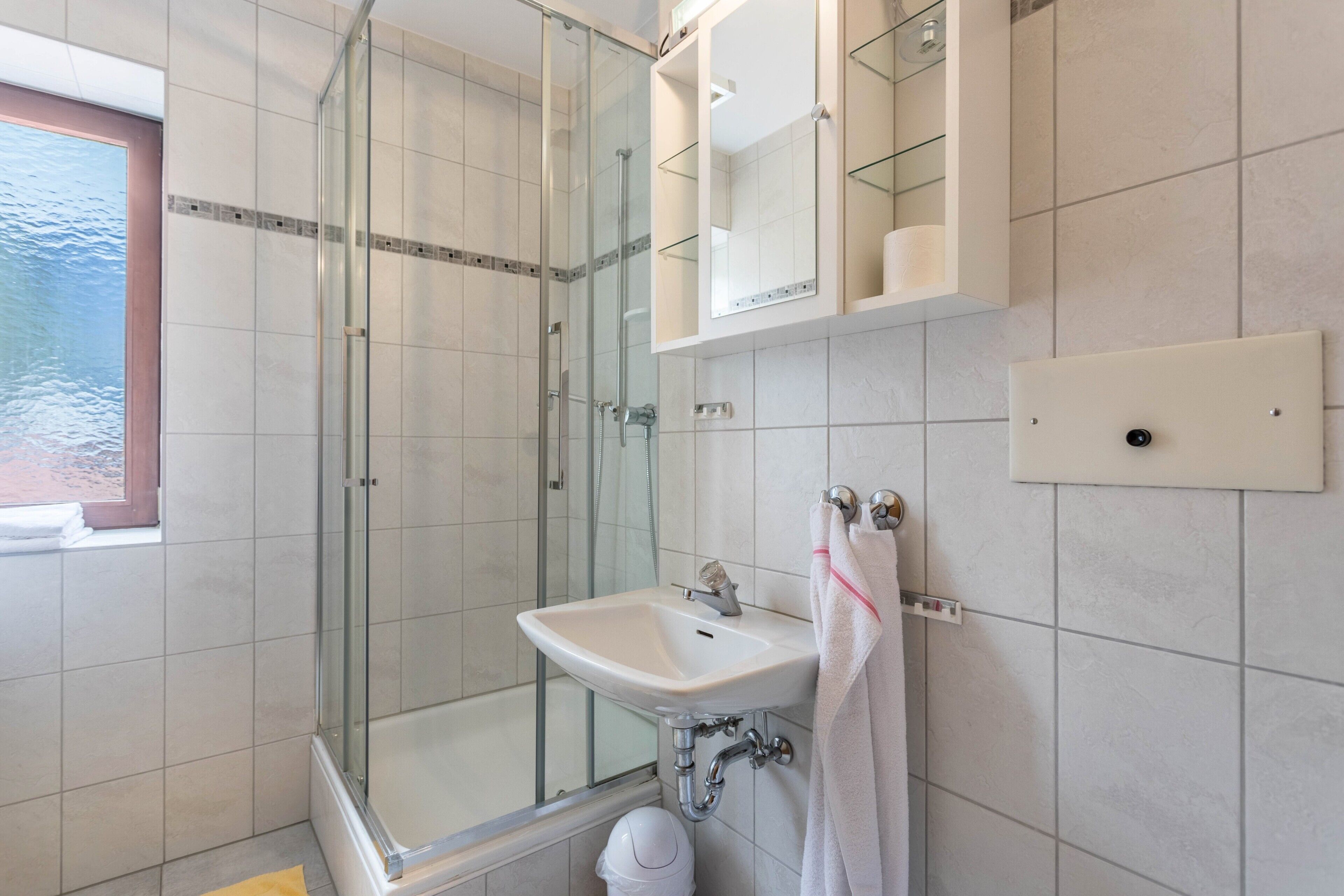 Ein modernes Badezimmer mit einer Duschkabine, einem Waschbecken und einem Spiegel.