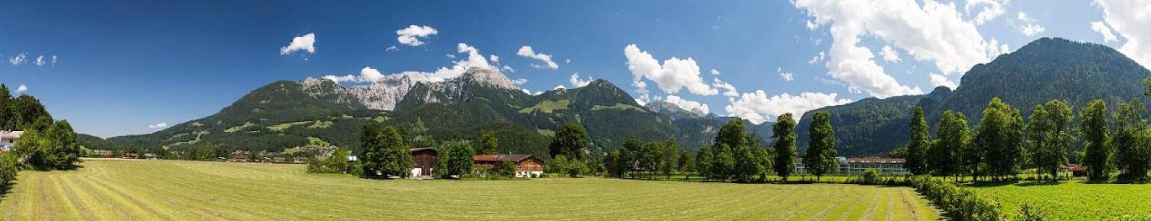 Una vista panoramica su un paesaggio montuoso con campi, case e alberi.