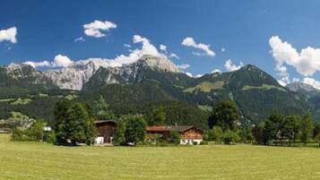 Una vista panoramica su un paesaggio montuoso con campi, case e alberi.