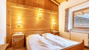 Ein Schlafzimmer mit Holzvertäfelung, einem Bett, Nachttischen und Wandleuchten.