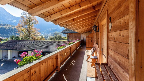 Ein Holzbalkon mit Bergblick, ein überdachter Bereich mit Bänken und ein Gebäude mit einem Ziegeldach.
