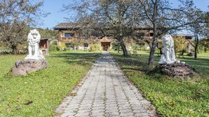 A paved pathway leading to a building with a traditional architectural style, surrounded by statues and greenery.