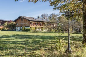 Een traditionele chalet met een balkon, zonnepanelen en een verzorgd gazon.