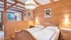 A wooden-paneled bedroom with a double bed, bedside lamps, and a hanging light fixture.