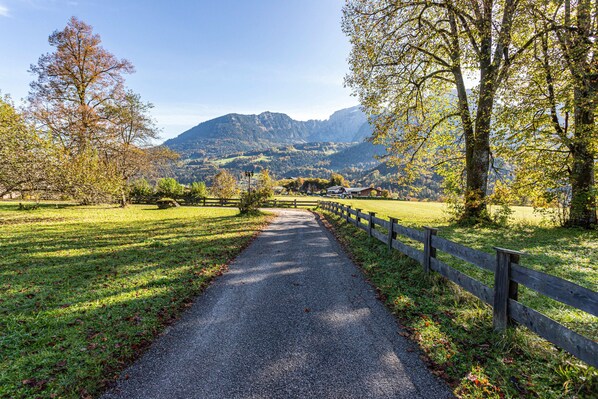 A gravel path with a wooden fence on one side, leading to a mountainous landscape.