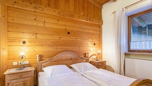 Une chambre aux murs lambrissés, avec deux lits, deux tables de chevet et une fenêtre avec des rideaux.