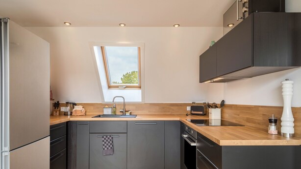 Een moderne keuken met een raam, ingebouwde apparatuur en houten aanrechtbladen.