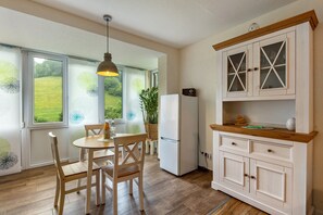 Una cucina con tavolo e sedie, frigorifero e pensile con vetri.