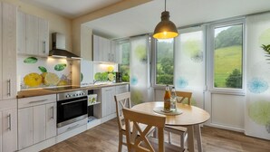 Eine moderne Küche mit weißen Schränken, einem eingebauten Backofen und einem Essbereich mit rundem Tisch und Stühlen.