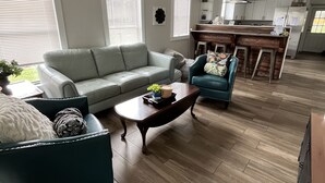 Un salón amplio con un sofá gris, un sillón azul y una mesa de centro de madera.