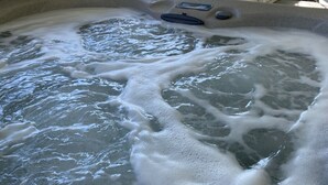 Un jacuzzi con vistas a un césped y árboles.