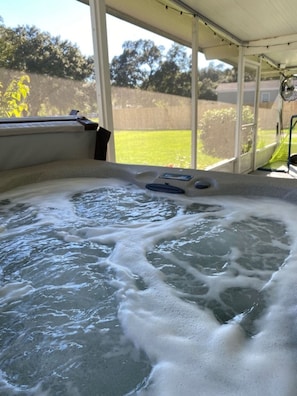 Un jacuzzi con vistas a un jardín con césped y árboles.