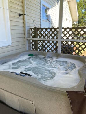 Un jacuzzi con cubierta de madera y una puerta blanca al fondo.