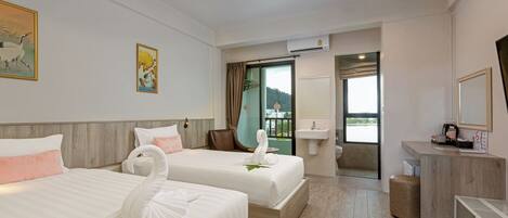 A hotel room with two beds, a desk, a sink, and a view of the outdoors.