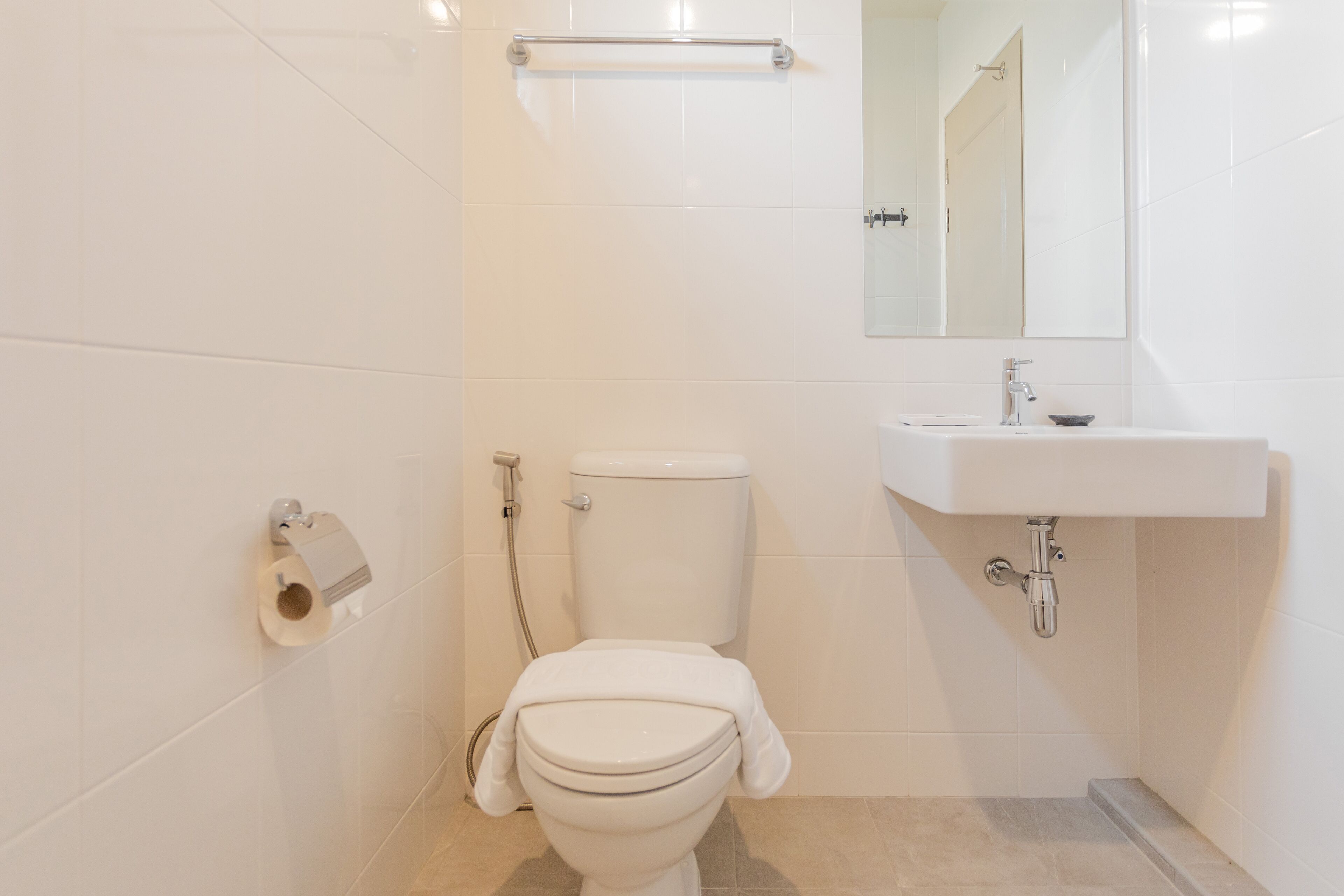 A bathroom with a toilet, sink, and mirror.