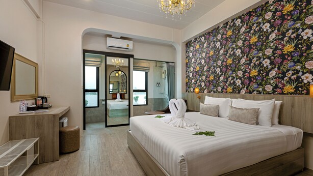 Una habitación de hotel moderna con una cama grande, un cabecero de madera, un papel tapiz floral y una araña.
