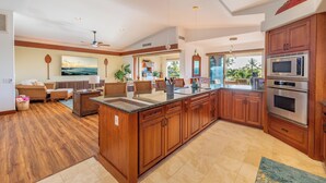 A spacious kitchen with wooden cabinets, a large island, and a built-in microwave. - Ohana Paradise@ Mauna Lani Villages, private beach club access (Waimea)