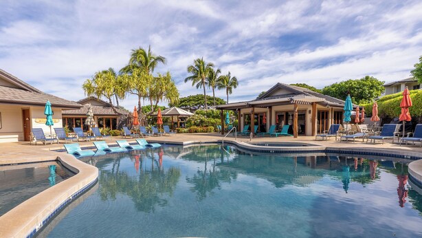 A pool area with lounge chairs and umbrellas, surrounded by palm trees and buildings. - Ohana Paradise@ Mauna Lani Villages, private beach club access (Waimea)