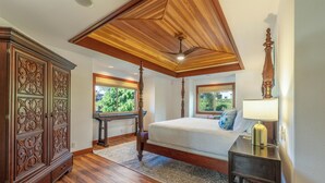 A bedroom with a wooden ceiling, a large bed, a nightstand, a dresser, and a window with a view of greenery. - Ohana Paradise@ Mauna Lani Villages, private beach club access (Waimea)