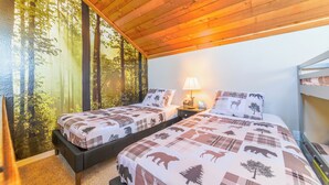 Ein Zimmer mit zwei Betten, einem Nachttisch mit Lampe und einem Schlafstockbett.