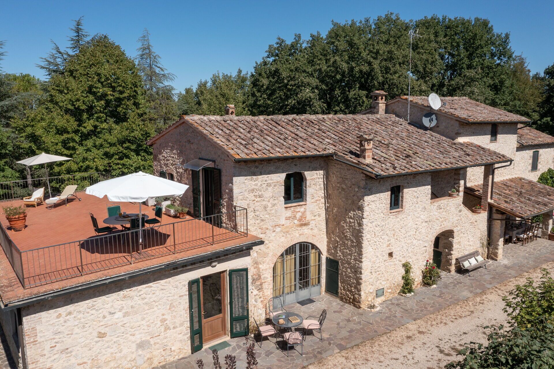 A stone building with a tiled roof, outdoor seating, and a satellite dish.