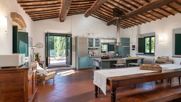 Una cocina amplia con comedor, ventanas grandes y techo rústico.