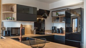 Una cocina moderna con una isla central, electrodomésticos negros y estantes de madera.