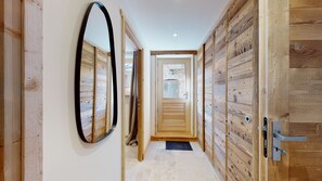 A hallway with wooden paneling, a large mirror, and a door leading to another room. - Lodge Alouette: Appartement Authentique Proche Pistes et Commerces (Champagny-en-Vanoise)