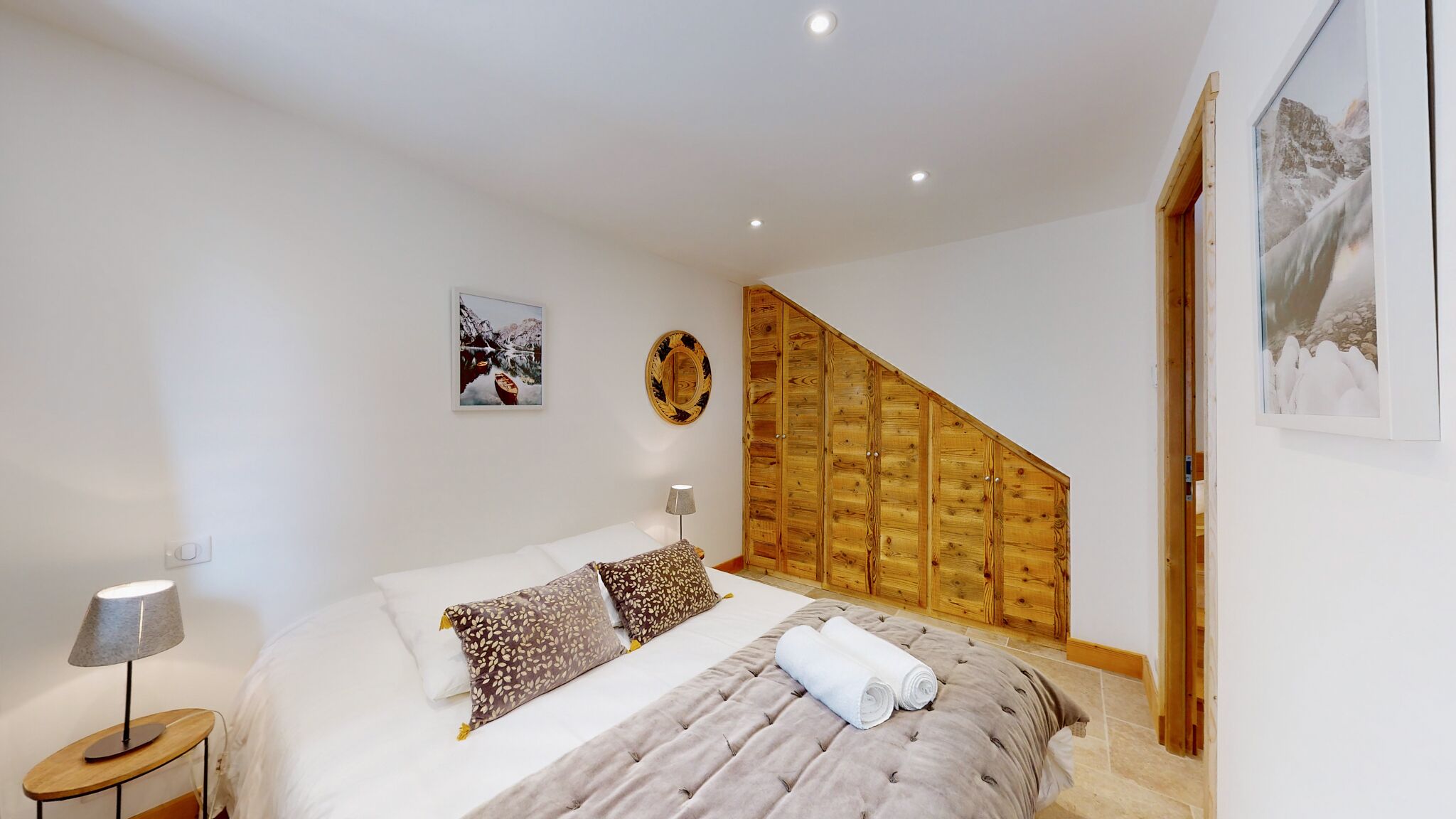 Ein Schlafzimmer mit einem Bett, einem Holzschrank, einem Nachttisch und zwei Wandleuchten.