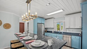 Une cuisine moderne dotée d’un îlot central, d’appareils électroménagers en acier inoxydable et de meubles de couleur bleu clair.