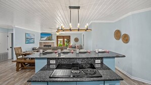 Une cuisine moderne dotée d’un plan de travail en granit, d’une cuisinière encastrée et d’un coin repas avec des chaises et une table en bois.