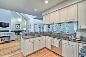 A modern kitchen with white cabinets, granite countertops, and a built-in oven.