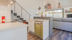 A modern kitchen with a built-in dishwasher, a grey sofa, and a staircase. - Loft Miro Apart Barcelona (Barcelona)