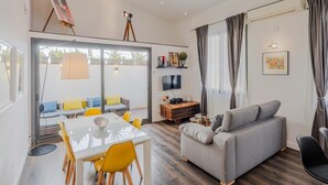 A modern living room with a sofa, dining table, and chairs, a TV, and a painting on the wall. - Loft Miro Apart Barcelona (Barcelona)
