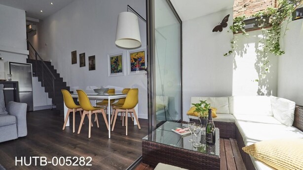 A modern living space with a dining area, a sofa, and a staircase. - Loft Miro Apart Barcelona (Barcelona)