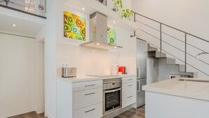 A modern kitchen with white cabinetry, a stainless steel oven, and a built-in dishwasher. - Loft Miro Apart Barcelona (Barcelona)