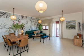 A spacious living area with a dining table, sofa, and two hanging lamps. - Sound Of The Mountain Chania (Chania)