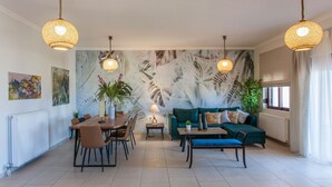 A spacious living area with a dining table, a sofa, and two hanging lamps. - Sound Of The Mountain Chania (Chania)