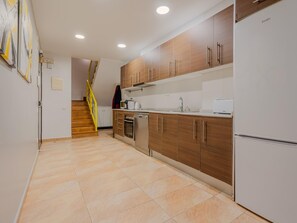 Uma cozinha moderna com armários de madeira, uma pia de aço inoxidável e um forno embutido.