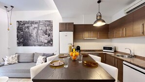 Eine moderne Küche mit Holzschränken, einem Esstisch mit weißen Stühlen und einem Stadtbild an der Wand.
