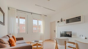 Moderni olohuone, jossa on sohva, pyöreä sohvapöytä sekä ruokailutila, jossa on pöytä ja tuolit.